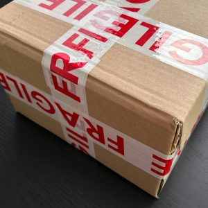 Cardboard box sealed with red fragile tape