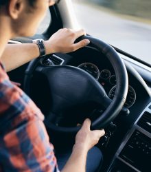 Close-up view of a man driving a modern car, showing dashboard and steering details.